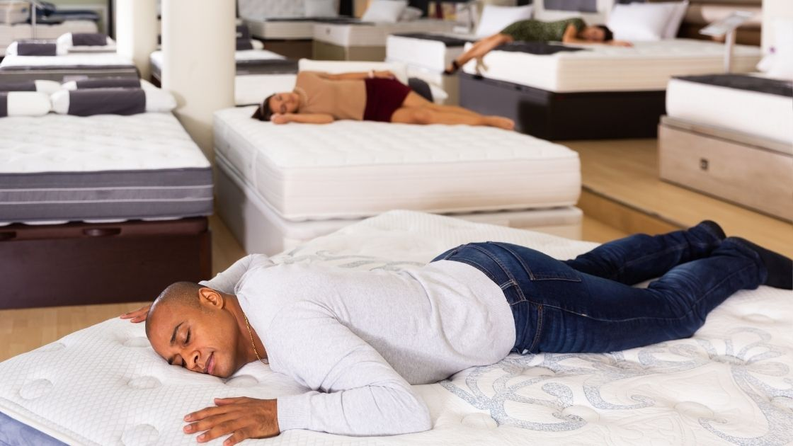 Picture of a mattress store with customers asleep on a bunch of mattresses